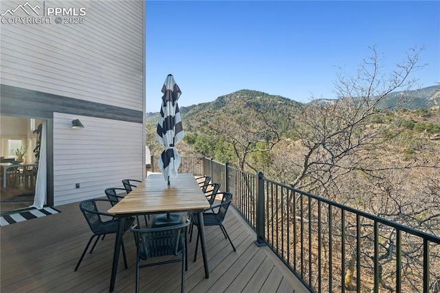 deck with a mountain view and outdoor dining area