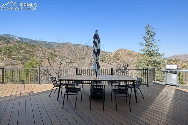 wooden terrace featuring outdoor dining area, a mountain view, and area for grilling