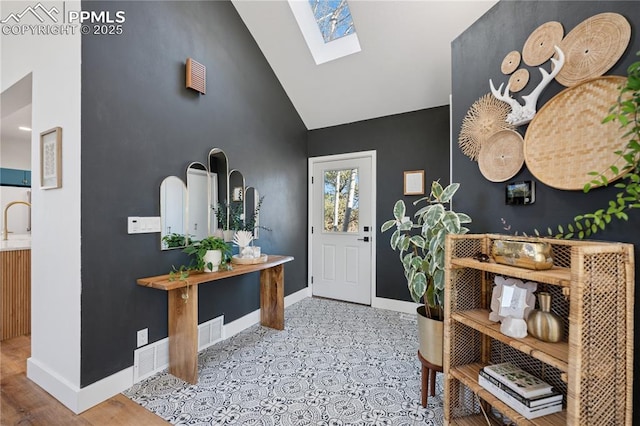 foyer with high vaulted ceiling, a skylight, visible vents, and baseboards