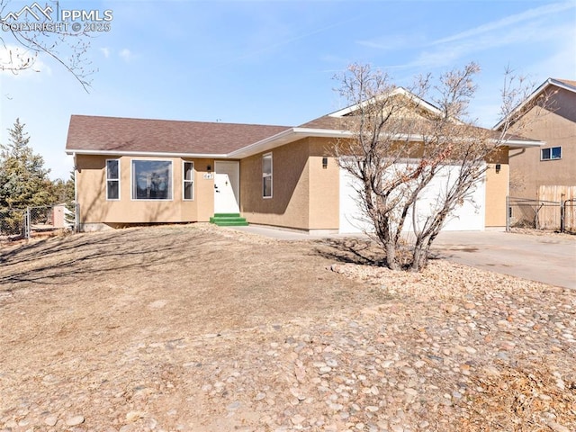 single story home featuring entry steps, concrete driveway, an attached garage, fence, and stucco siding