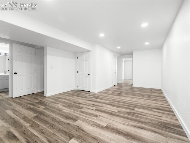 interior space with baseboards, wood finished floors, and recessed lighting