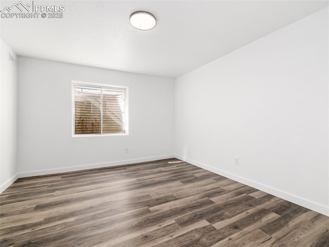 unfurnished room featuring dark wood-style flooring and baseboards