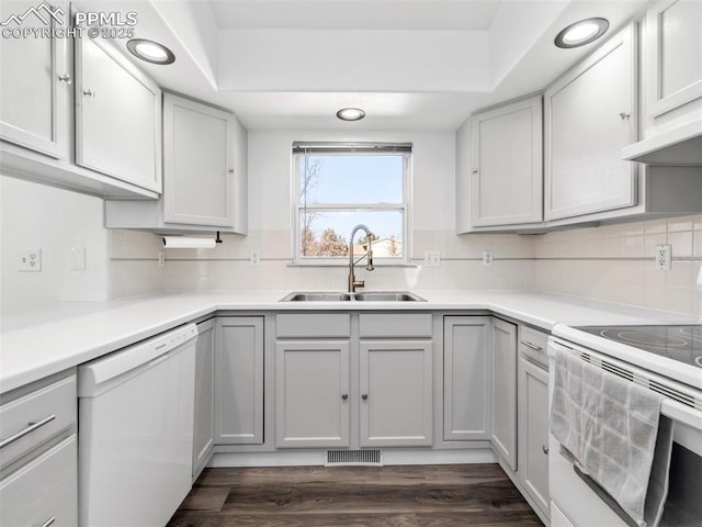 kitchen featuring white appliances, a sink, dark wood finished floors, and decorative backsplash