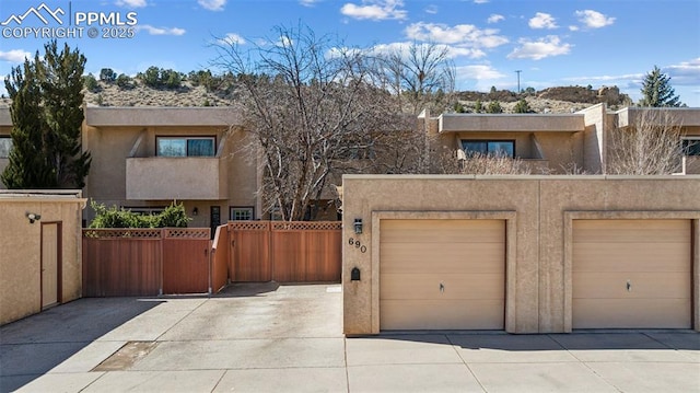 view of front of property featuring a garage, fence, driveway, a gate, and stucco siding