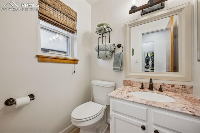 half bath featuring toilet, baseboards, and vanity