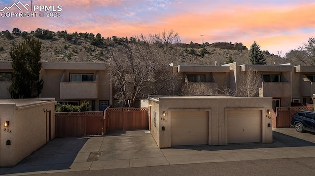 view of front of home with a garage, driveway, fence, and stucco siding