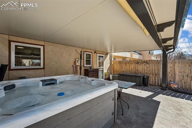 view of patio / terrace featuring fence and a hot tub