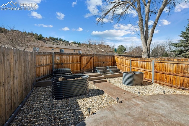 view of patio with a fenced backyard and a vegetable garden