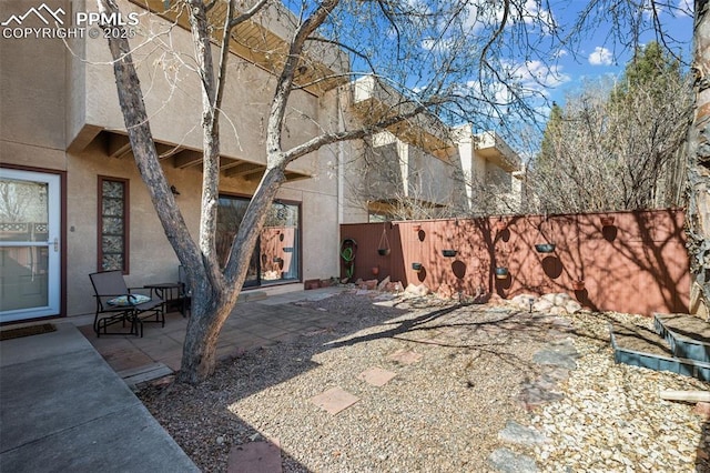 rear view of property with a patio area, fence, and stucco siding