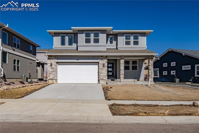 prairie-style home featuring central AC unit, concrete driveway, stone siding, an attached garage, and stucco siding