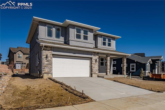 prairie-style house with driveway, stone siding, an attached garage, and stucco siding