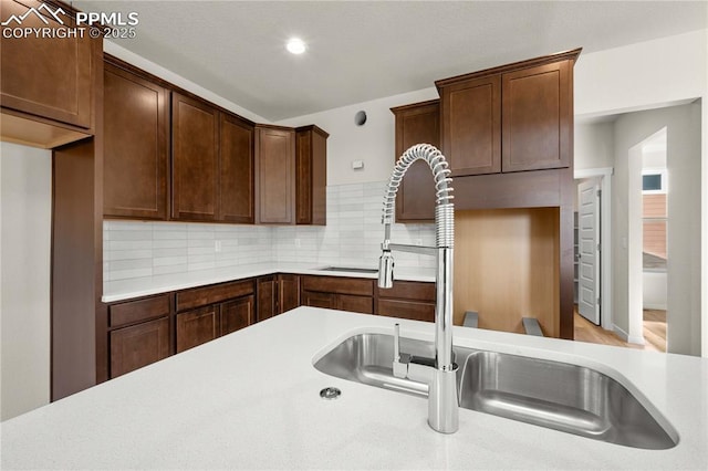 kitchen featuring light countertops, dark brown cabinets, a sink, and decorative backsplash