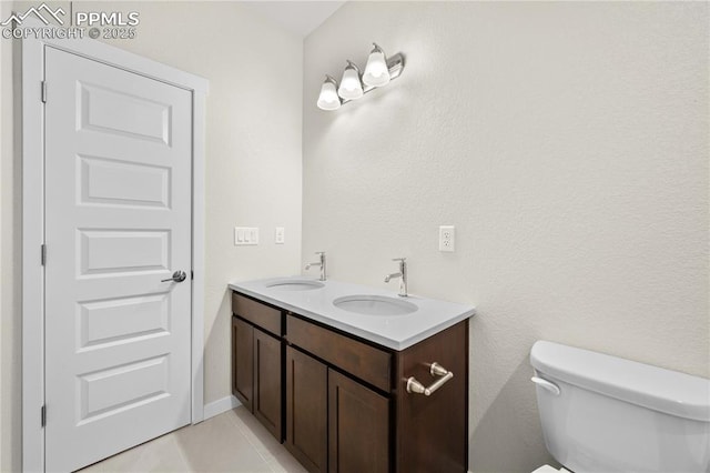 bathroom with tile patterned floors, a sink, toilet, and double vanity