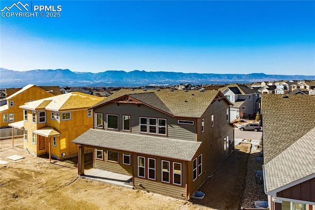 back of house with a shingled roof, a residential view, and a mountain view