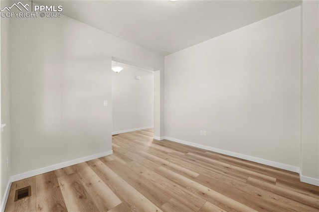 empty room featuring baseboards, visible vents, and light wood finished floors