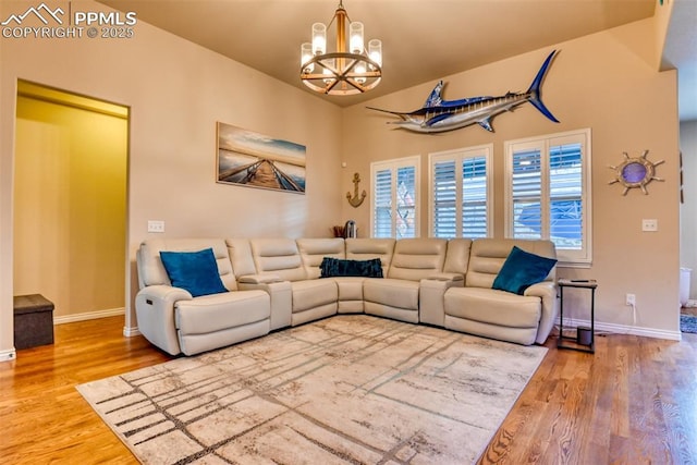 living area featuring baseboards, a chandelier, and wood finished floors