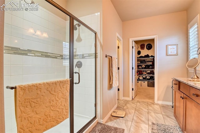 bathroom featuring a stall shower, a walk in closet, vanity, and baseboards