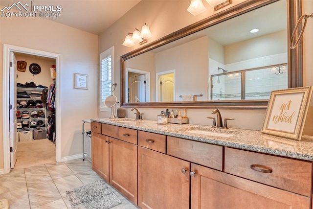 bathroom with double vanity, a spacious closet, a stall shower, and a sink