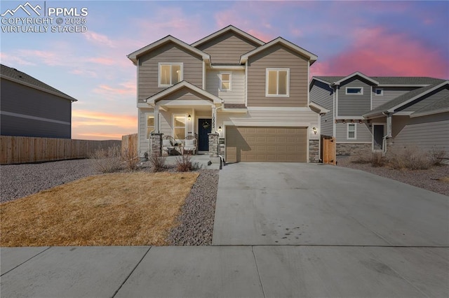 craftsman inspired home with a garage, stone siding, fence, and concrete driveway