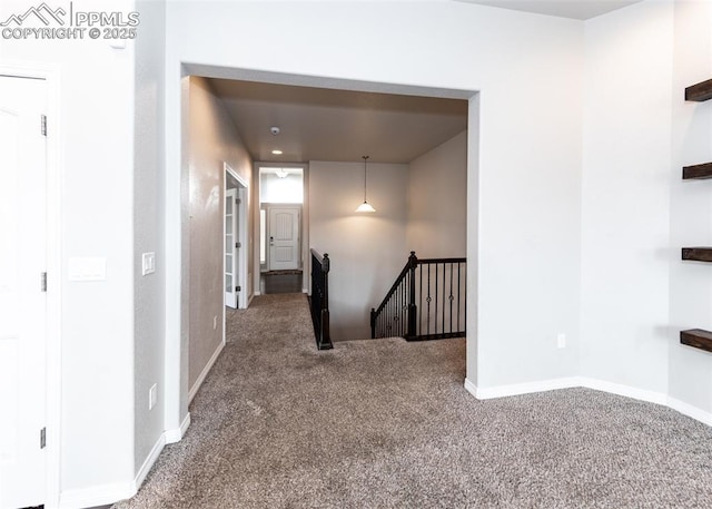 corridor featuring carpet floors, baseboards, and an upstairs landing