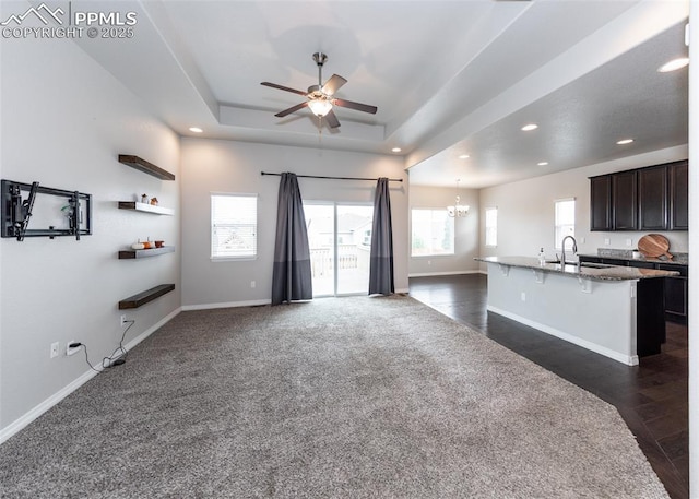 kitchen featuring a sink, open floor plan, a kitchen bar, plenty of natural light, and a raised ceiling