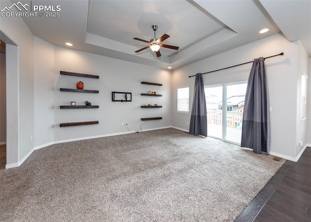 unfurnished living room featuring a ceiling fan, a tray ceiling, baseboards, and recessed lighting