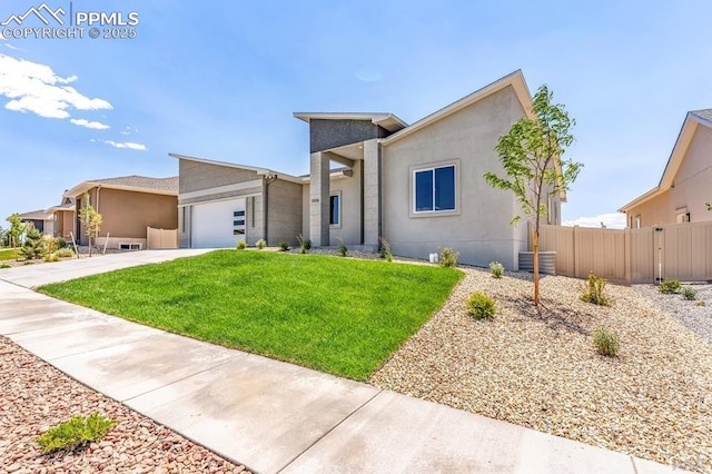 view of front of home featuring a front yard, fence, driveway, an attached garage, and stucco siding