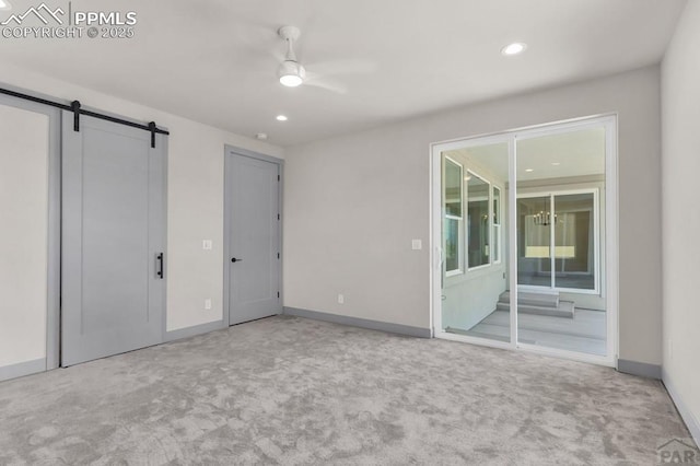 carpeted empty room with a barn door, recessed lighting, and baseboards