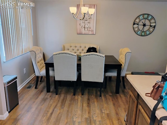 dining area featuring a notable chandelier, baseboards, visible vents, and wood finished floors