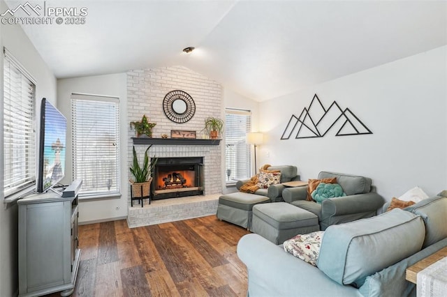 living room featuring vaulted ceiling, dark wood-style flooring, and a brick fireplace