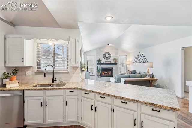 kitchen with white cabinets, dishwasher, a peninsula, vaulted ceiling, and a sink