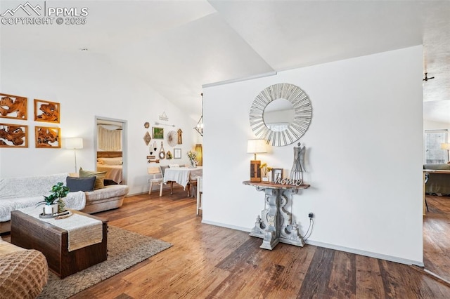 living room featuring vaulted ceiling, baseboards, and wood finished floors