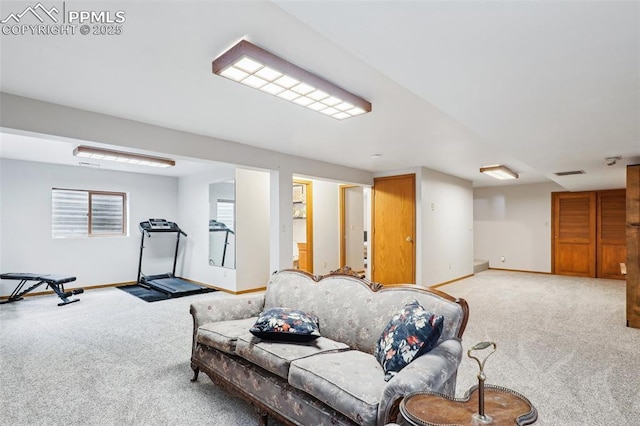 living area featuring baseboards, visible vents, and light colored carpet