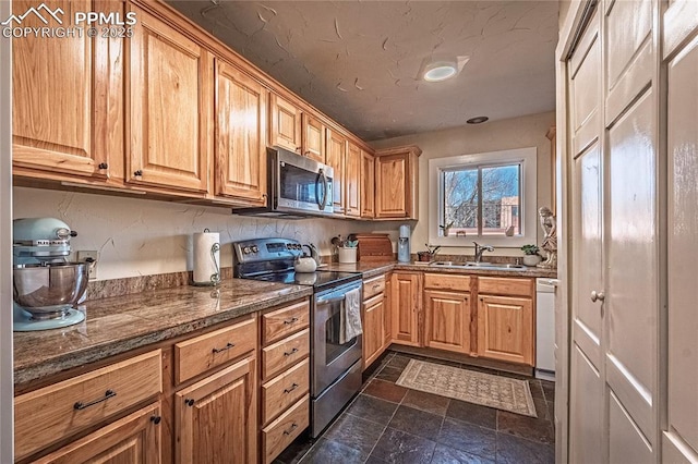 kitchen featuring stainless steel appliances, stone finish floor, and a sink