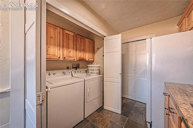 laundry room featuring stone finish floor, washing machine and dryer, and cabinet space