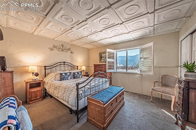 bedroom with a wainscoted wall, a textured wall, carpet, and an ornate ceiling