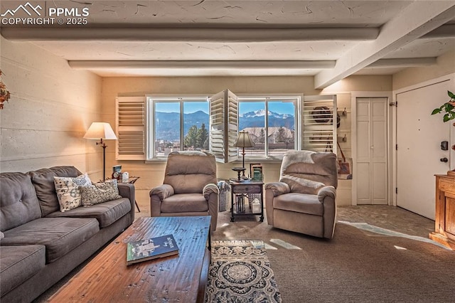 living area with a mountain view, carpet flooring, and beam ceiling