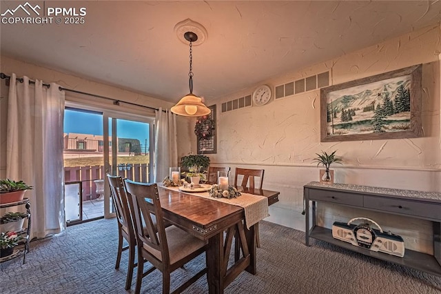 carpeted dining area with a textured wall and visible vents