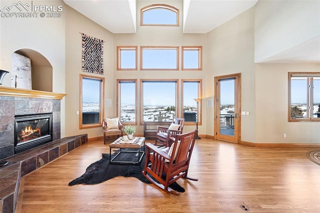 living area featuring a healthy amount of sunlight, wood finished floors, and a tile fireplace