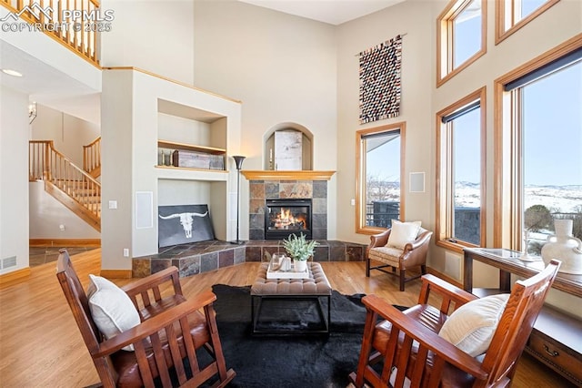 living area with a healthy amount of sunlight, a tiled fireplace, and wood finished floors