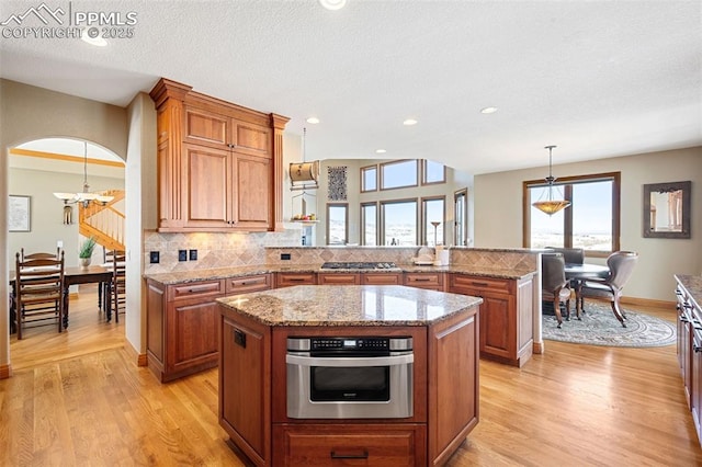 kitchen featuring brown cabinets, appliances with stainless steel finishes, and arched walkways