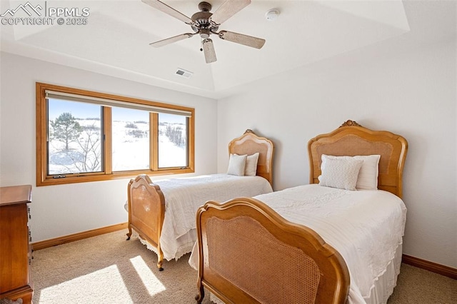 carpeted bedroom featuring a tray ceiling, visible vents, ceiling fan, and baseboards