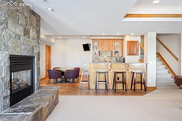 kitchen with carpet, a breakfast bar, a fireplace, and tile patterned floors