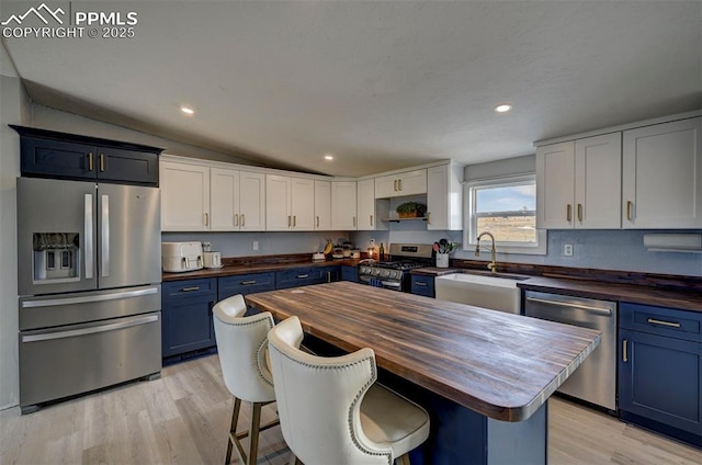 kitchen featuring lofted ceiling, wood counters, a breakfast bar area, stainless steel appliances, and blue cabinetry