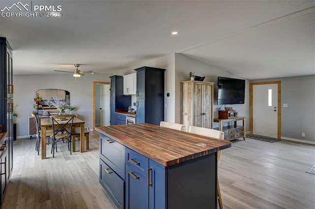 kitchen with vaulted ceiling, wooden counters, blue cabinets, and light wood-style floors