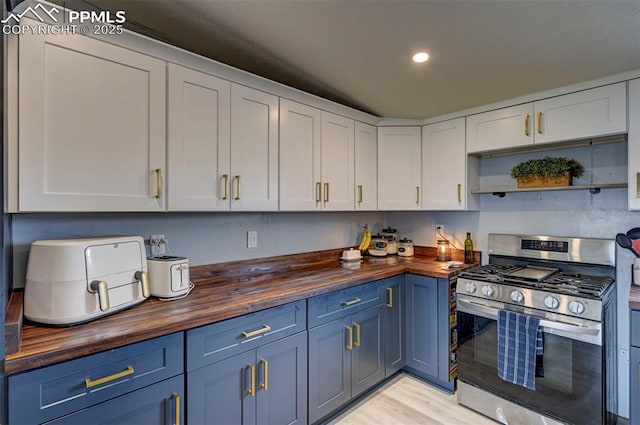 kitchen featuring blue cabinets, butcher block counters, white cabinets, light wood finished floors, and gas stove