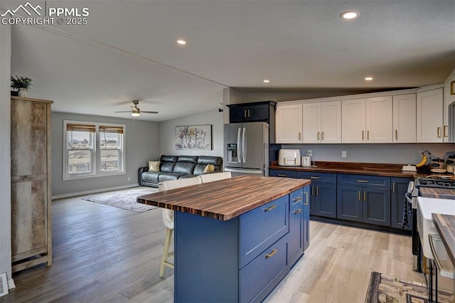 kitchen featuring white cabinets, butcher block countertops, appliances with stainless steel finishes, and blue cabinets