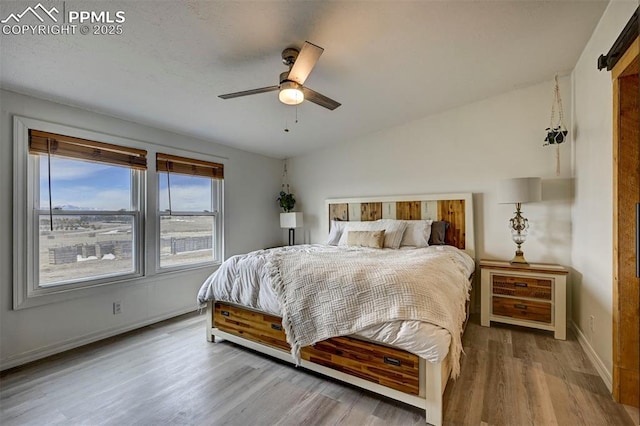 bedroom featuring a ceiling fan, lofted ceiling, baseboards, and wood finished floors