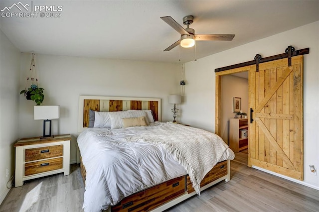 bedroom with a barn door, ceiling fan, and wood finished floors