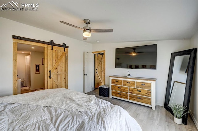 bedroom with a barn door, a ceiling fan, and wood finished floors